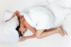 What is hypnotherapy used for? Solving sleep issues. Woman covered by duvet.