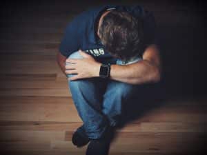 What is hypnotherapy used for? Alleviating depression. A man head on knees.