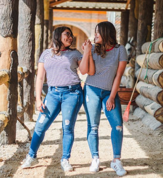 Self-compassion two girls wearing jeans and striped tops holding hands