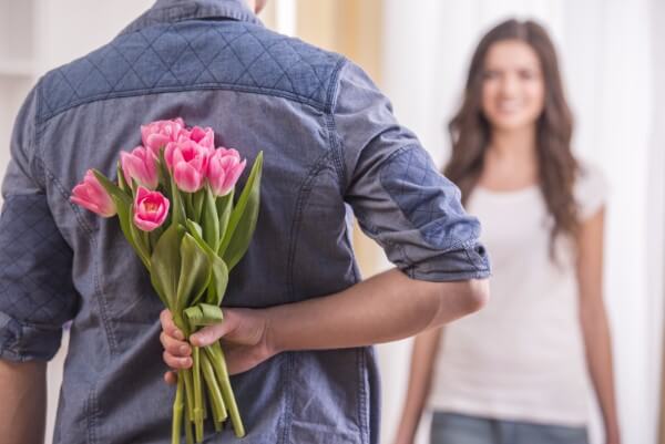 Person holding flowers behind their back, in front of woman with dark hair. Boundaries blog.