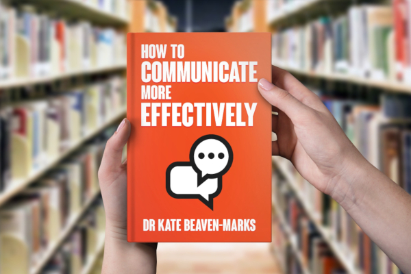 Person in library holding a copy of How to Communicate More Effectively by Dr Kate Beaven-Marks