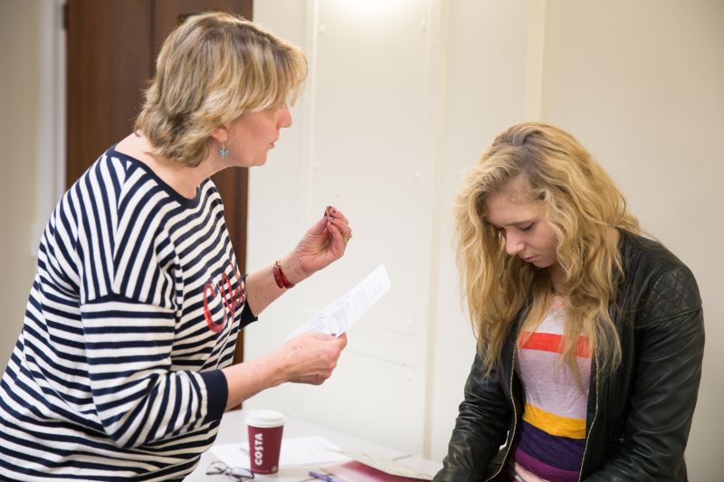 Hypnotherapists - two women, one in a striped top hypnotising one in a leather jacket.