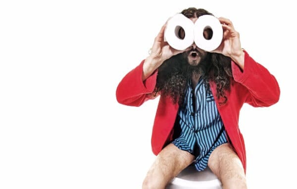 Man on the toilet, using toilet rolls as pretend binoculars.