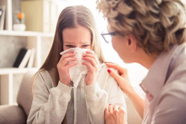 Woman seeing a hypnotherapist, crying and being comforted