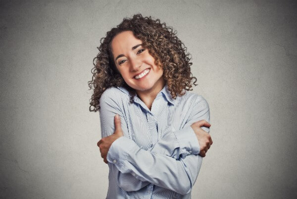 Woman hugging her self, smiling.